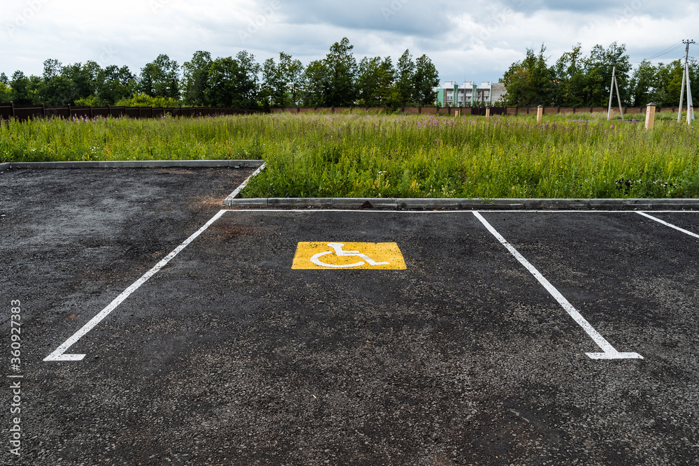 Obraz premium a yellow sign on the asphalt shows a Parking place for people with disabilities, for the disabled, a road sign, markings on the road