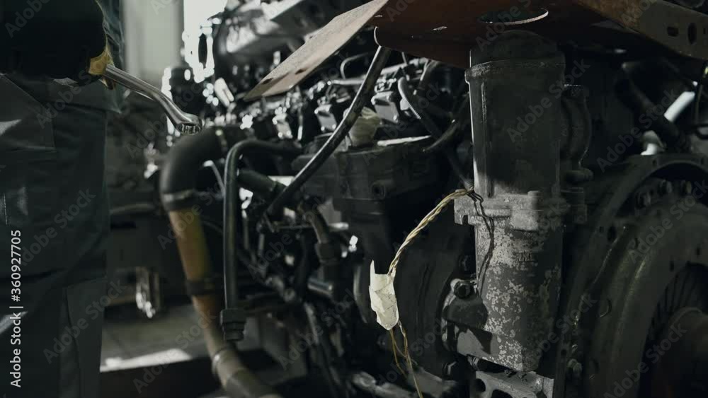 Close Up Of Mechanic With Wrench In His Hand Standing In Front Of Bus Engine Estimating Needed Repairs. Close Up Of Mechanic With Wrench In His Hand Standing In Front Of Bus Engine Estimating Needed Repairs.
