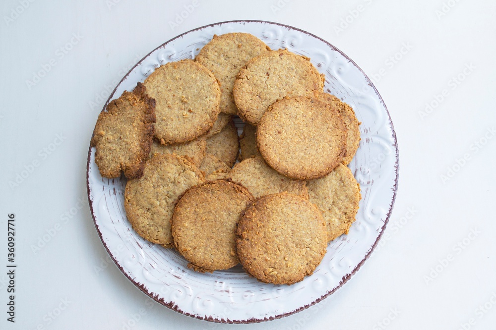 Composition of homemade macaroons in a light clay plate, on a light background. Top view