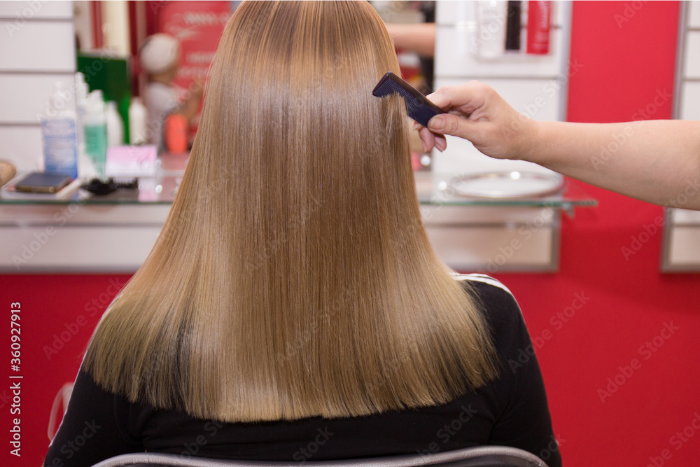Hairdresser combs girl's hair after haircut and dyeing Hairdresser combs girl's hair after haircut and dyeing