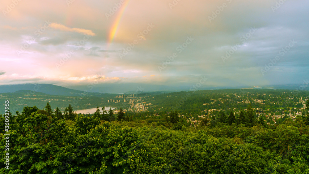 Rainbow tail highlights dark clouds over distant mountains