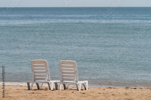 Deck chair in the sand on the shore. Relax  relaxation on the beach. Blue water in the ocean sea.