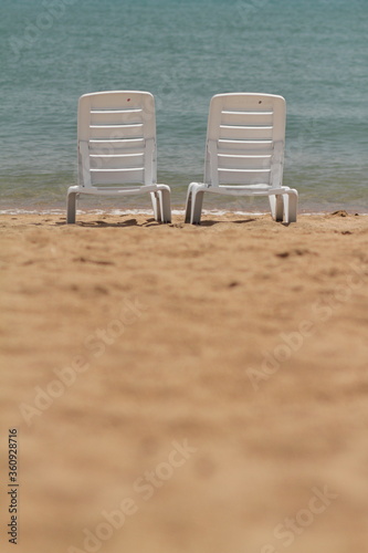 Deck chair in the sand on the shore. Relax, relaxation on the beach. Blue water in the ocean sea.