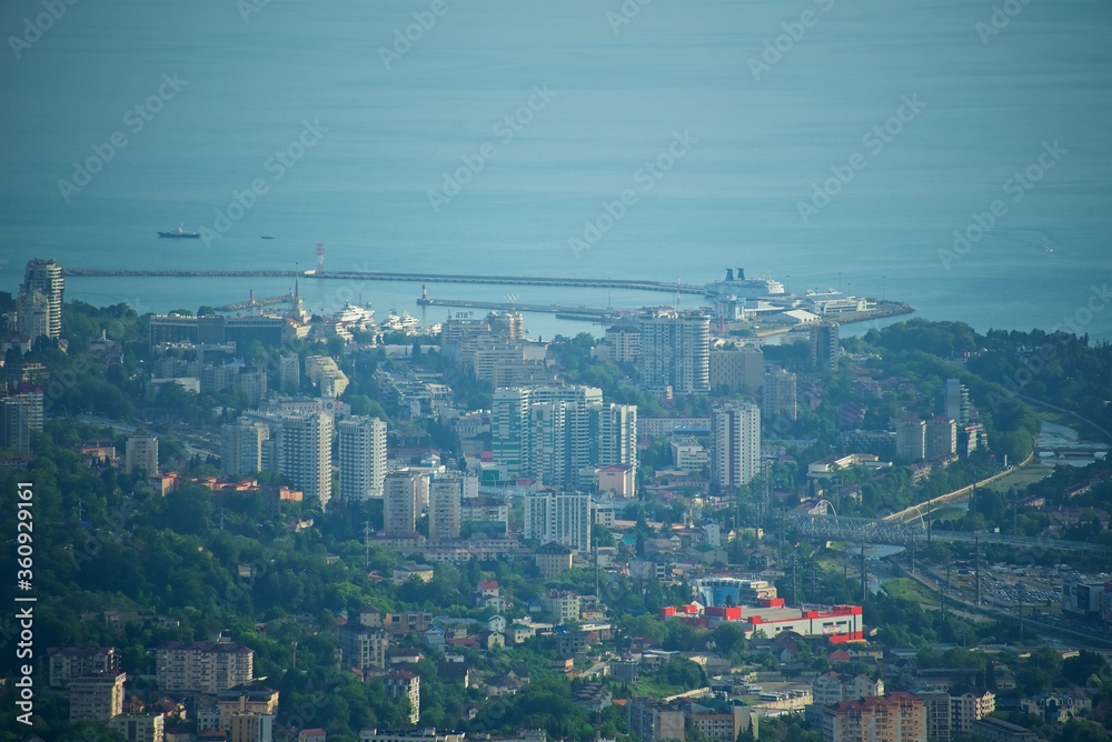 Panorama of the center of the coastal city. Lots of buildings and roads. Ships at sea. The seaport is visible. The river flows in the valley. View of the city of Sochi from above.