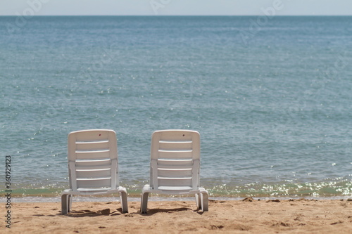 Deck chair in the sand on the shore. Relax, relaxation on the beach. Blue water in the ocean sea. © Maksim Selin
