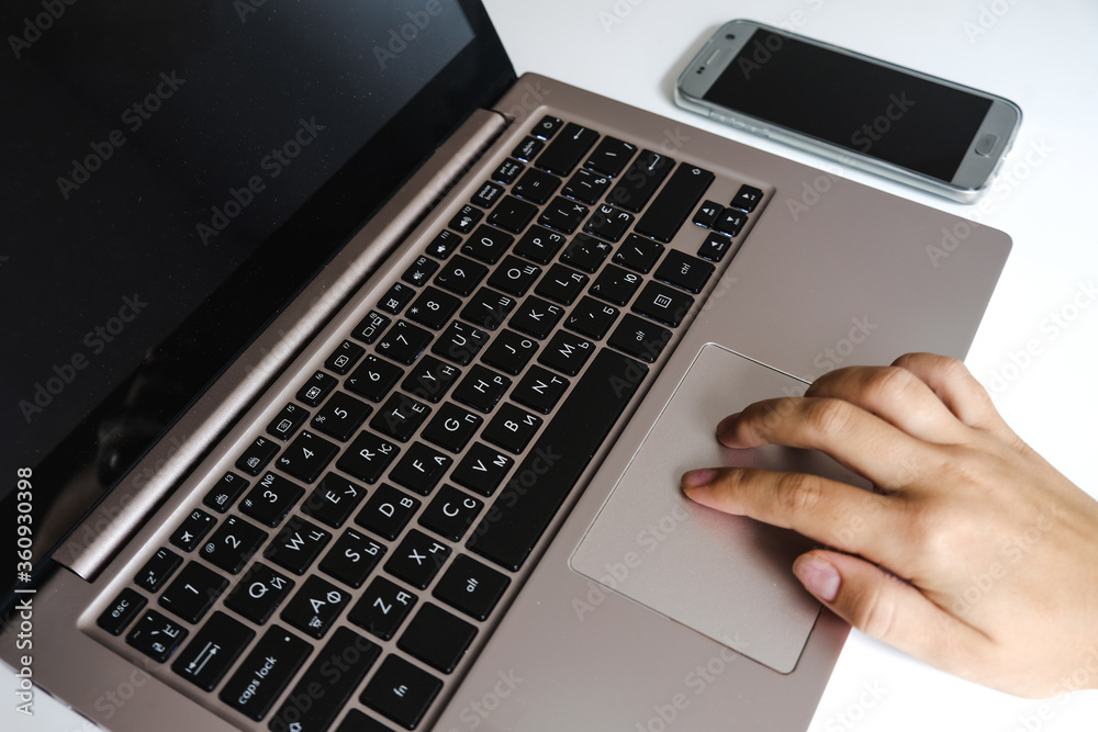Two white female fingers using laptop touchpad gesture. Modern home office workspace. Using computer and smartphone for working and studying, homeschooling and lifestyle communication through Internet Two white female fingers using laptop touchpad gesture. Modern home office workspace. Using computer and smartphone for working and studying, homeschooling and lifestyle communication through Internet
