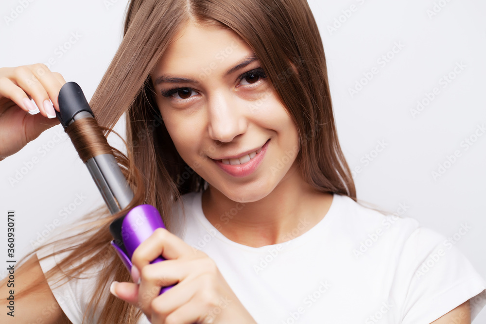 Beautiful young female model takes care of her hair and uses a hair straightener Beautiful young female model takes care of her hair and uses a hair straightener