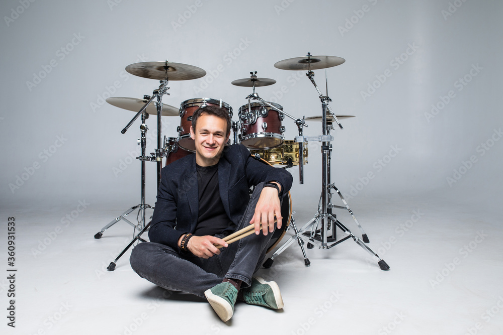 Young handsome man in suit sitting in front of drum set isolated on white background Young handsome man in suit sitting in front of drum set isolated on white background