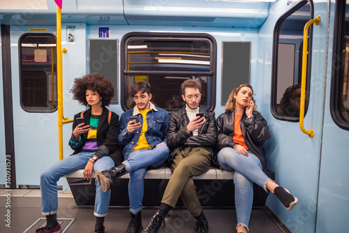 Wallpaper Mural Group of friends using smartphones while traveling by metro Torontodigital.ca