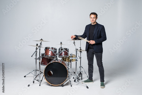 Young man standing on drum set isolated on white background