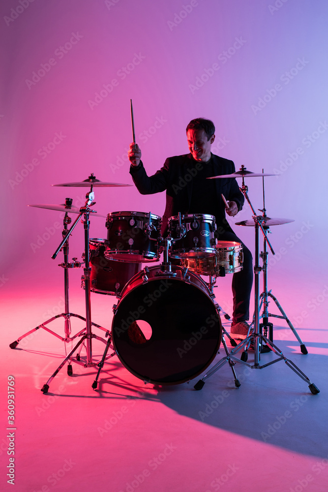 Fototapeta premium Young man drummer playing on drums on music concert. Club lights, artist show.