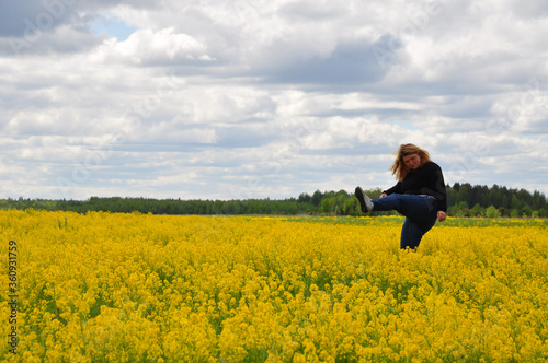 Young woman girl in black clothes in the field full of yellow flowers