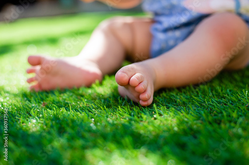 baby's feet in summer on the green lawn, close-up, space for text