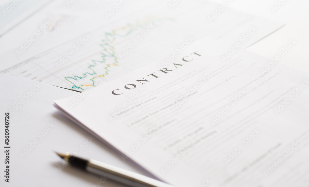 Contract paper and pen on white desk background. Focus on title Contract. Defocused pencil. Contract paper and pen on white desk background. Focus on title Contract. Defocused pencil.
