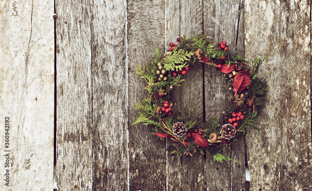 Home made christmas wreath hanging on a rustic wooden wall.