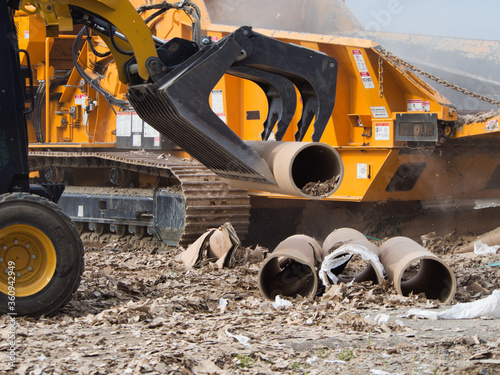 Photography A skid steer using a grapple bucket to pick up and recycle tubes