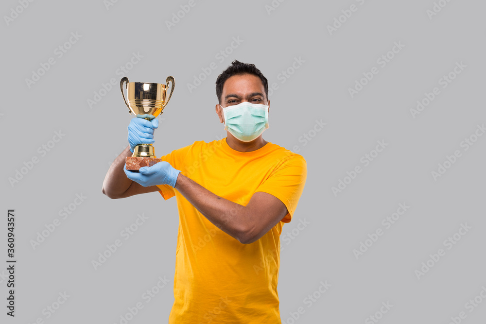 Indian Man Holding Trophy in Hands WEaring Medical Mask and Gloves Isolated