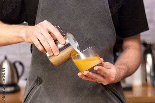 latte art. art of drawing on coffee. barista makes latte art milk from a pitcher