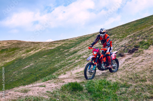 A beautiful landscape of the red mountain with a motorcyclist. Motocross competition.