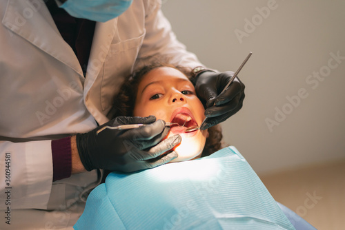 dentist attending with his instruments to a girl who is quietly in the clinic