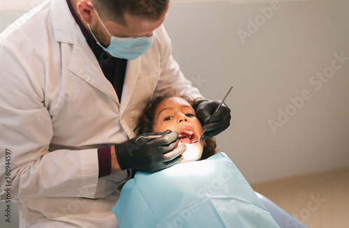 dentist performing care for a girl in the hospital, inspecting her mouth