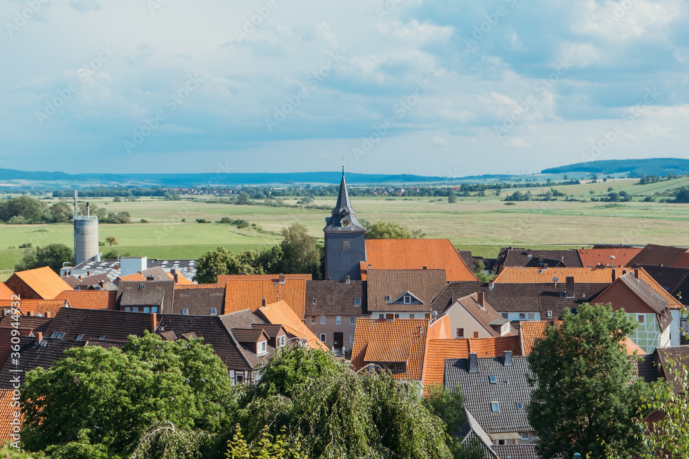 Aerial view on the roofs of a European village with a spire of a Catholic church against a blue sky. German old settlement. Place for text