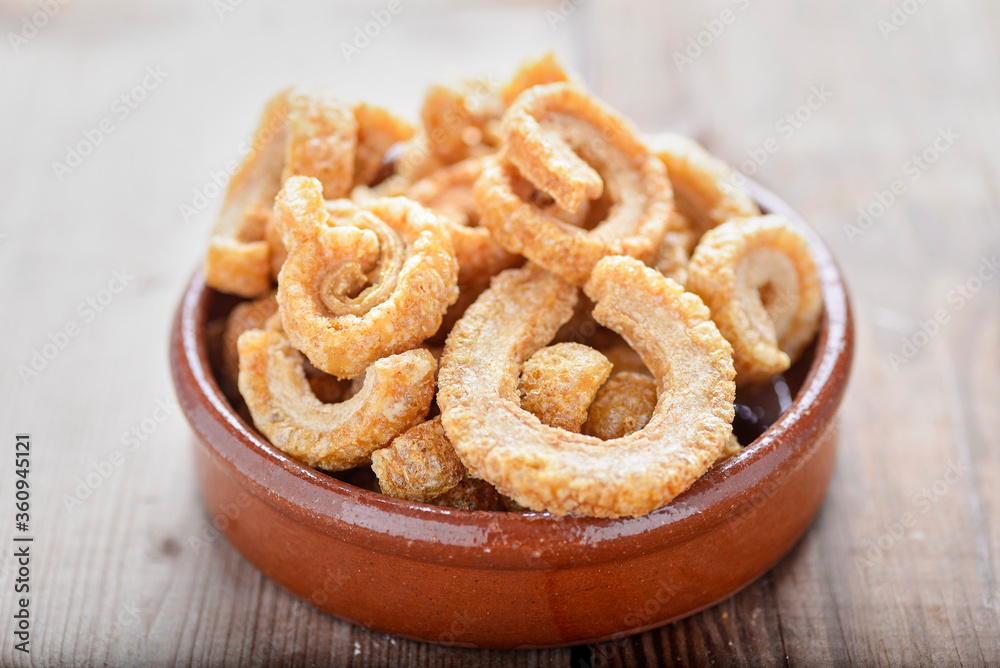 Fototapeta premium fried pork rinds, in a rustic container on a wooden background