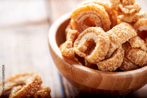 fried pork rinds, in a rustic container on a wooden background photo