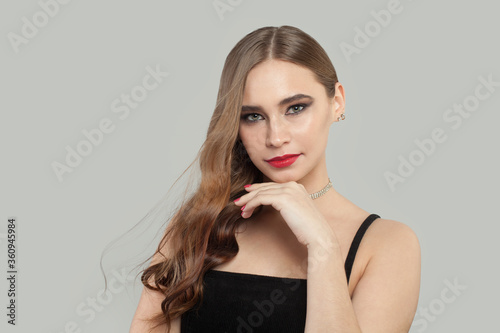Perfect young woman with red lips makeup and long brown curly hair portrait