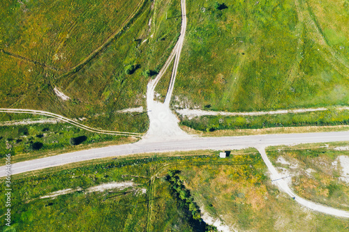 Aerial view of road between green meadow hills, top view.
