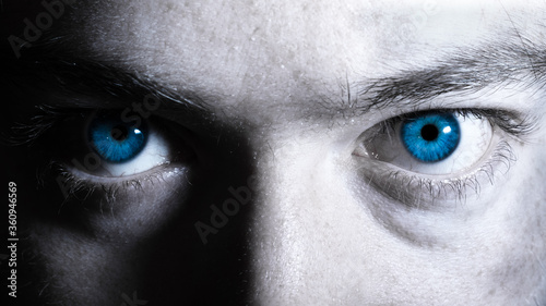 Bright blue eyes of a man close up black and white portrait. Vibrant colorful dramatic eyes background. Window to the soul concept