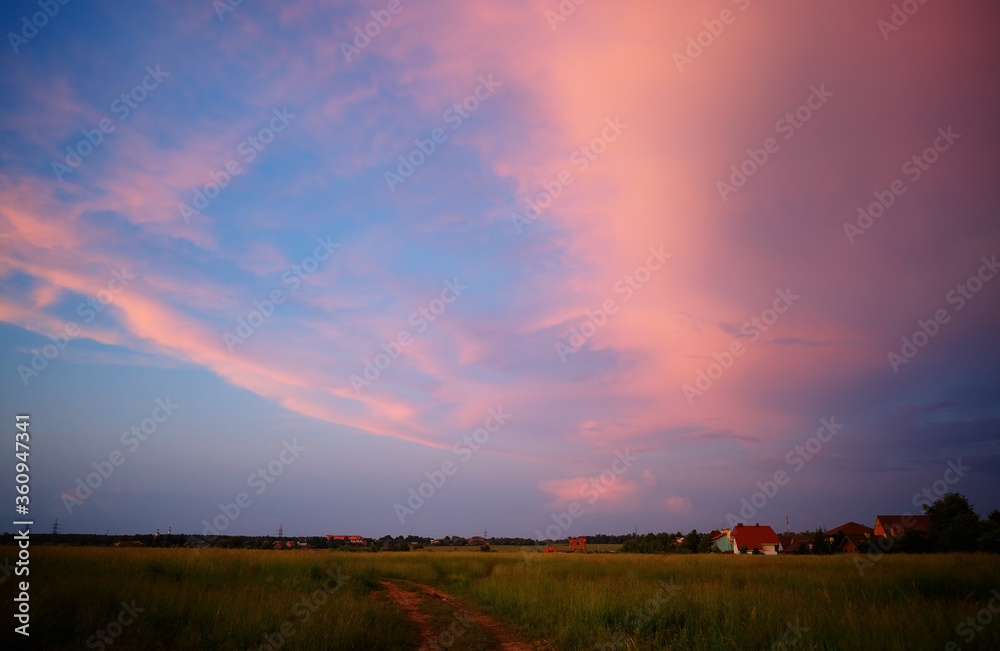 Burning clouds over the sunset meadow background