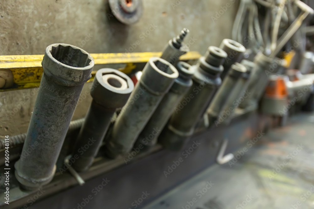 Industrial drill bits of various shapes and size in a concrete plant factory tools storage above the workbench. With some blurry tools in the background Industrial drill bits of various shapes and size in a concrete plant factory tools storage above the workbench. With some blurry tools in the background