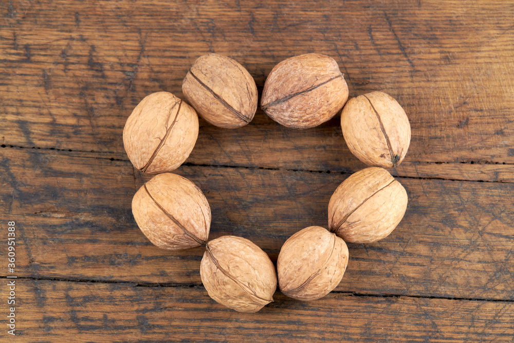 group of fresh raw walnuts on old wooden board background. rustic and detailed image. heart shape. group of fresh raw walnuts on old wooden board background. rustic and detailed image. heart shape.