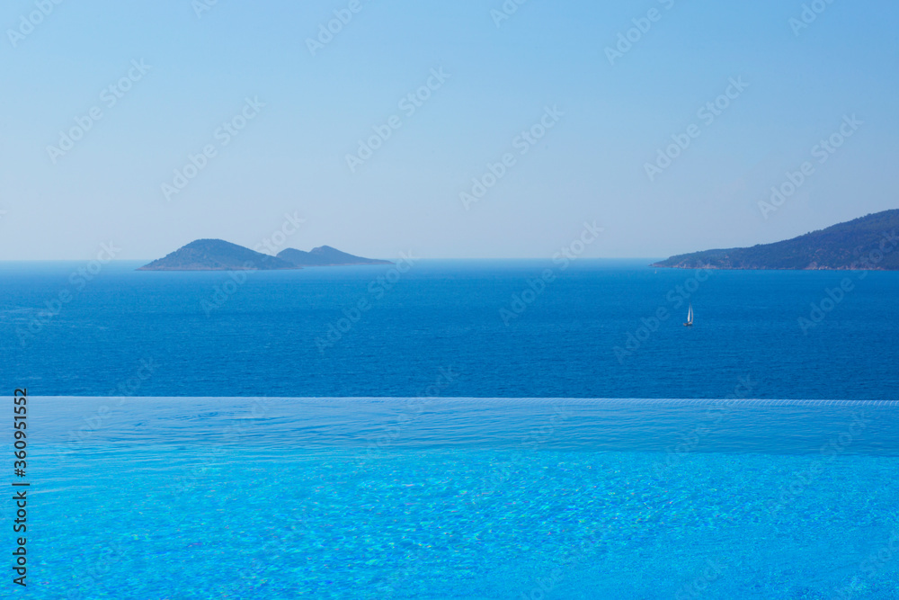 Infinity swimming pool with sea on bright summer day