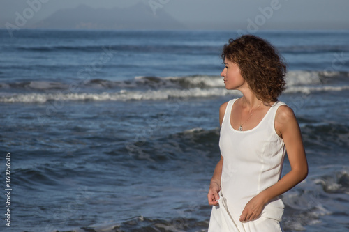 Woman in white dress walking near a beach in sunny summer day  clear sky