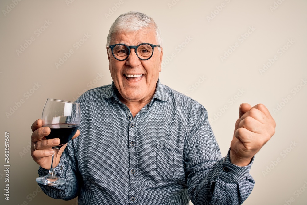 Senior handsome hoary man drinking glass of red wine over isolated white background screaming proud and celebrating victory and success very excited, cheering emotion Senior handsome hoary man drinking glass of red wine over isolated white background screaming proud and celebrating victory and success very excited, cheering emotion