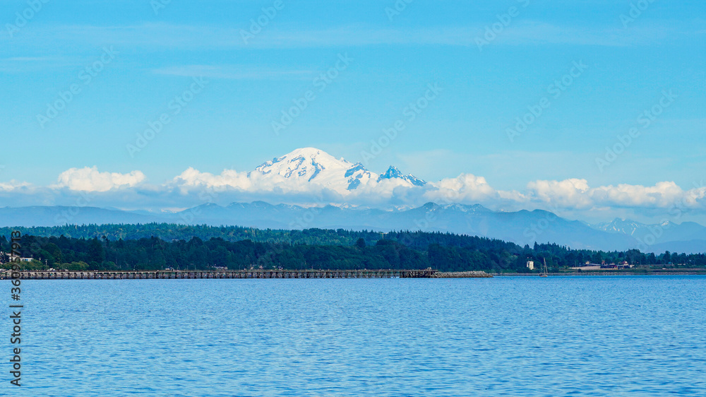 Washington, USA. View over the mirroring water of the Pacific ocean with Snow Capped Mount Baker Mountains in the background. 