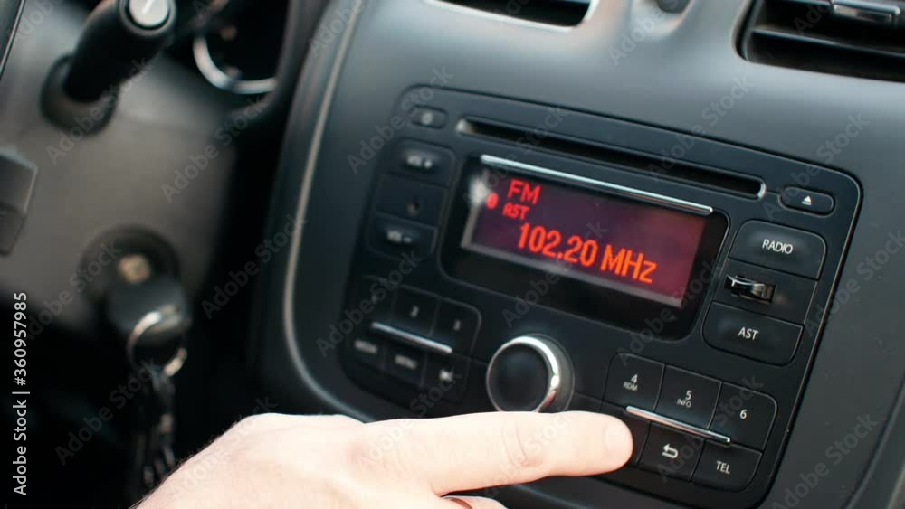 Radio and music in the car. Driver tunes car radio to media radio station frequency Radio and music in the car. Driver tunes car radio to media radio station frequency