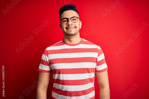 Wallpaper Mural Young handsome man wearing casual striped t-shirt and glasses over isolated red background with a happy and cool smile on face. Lucky person. Torontodigital.ca
