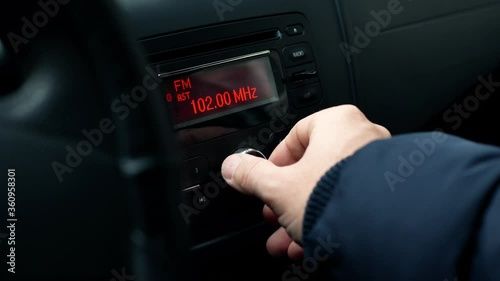 Radio and music in the car. Driver tunes car radio to media radio station frequency 