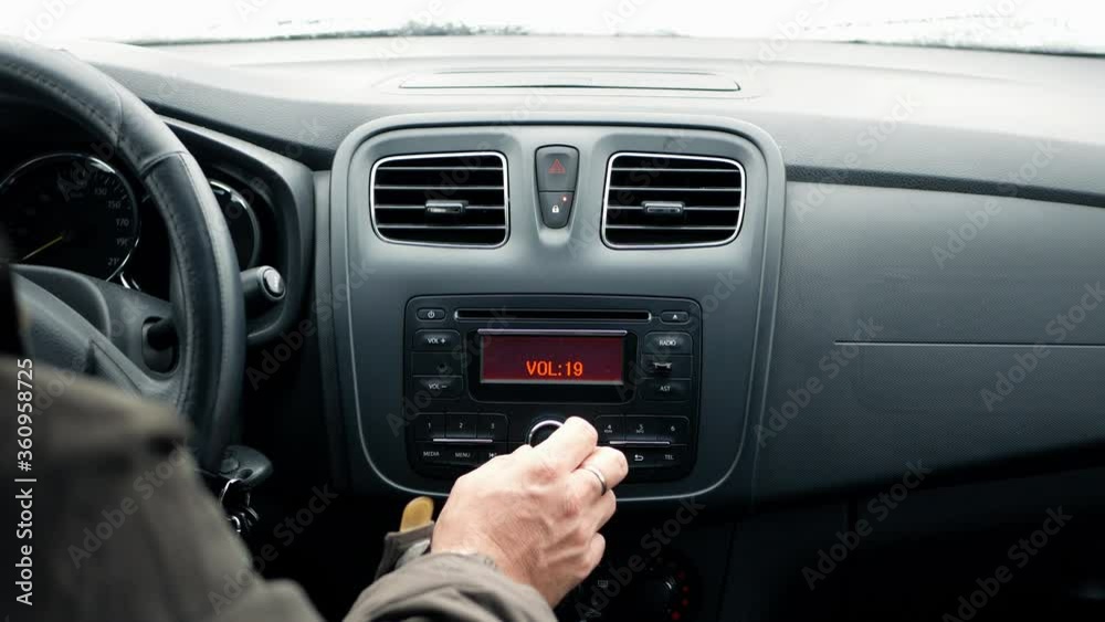 Radio and music in the car. Driver tunes car radio to media radio station frequency 