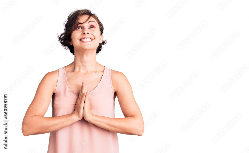 Beautiful young woman with short hair wearing casual style with sleeveless shirt begging and praying with hands together with hope expression on face very emotional and worried. begging. Beautiful young woman with short hair wearing casual style with sleeveless shirt begging and praying with hands together with hope expression on face very emotional and worried. begging.