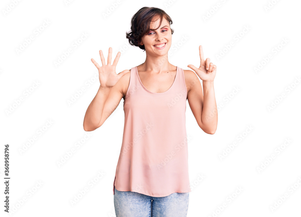 Beautiful young woman with short hair wearing casual style with sleeveless shirt showing and pointing up with fingers number seven while smiling confident and happy. Beautiful young woman with short hair wearing casual style with sleeveless shirt showing and pointing up with fingers number seven while smiling confident and happy.