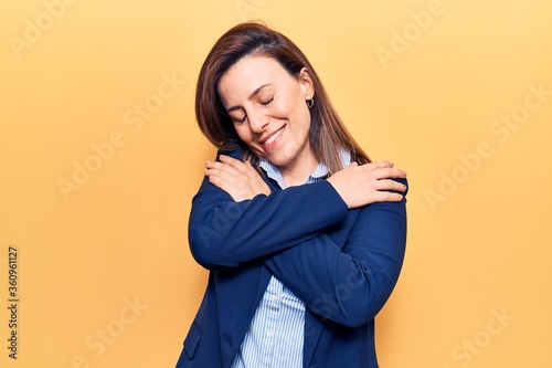 Photos Young beautiful woman wearing business clothes hugging oneself happy and positive, smiling confident