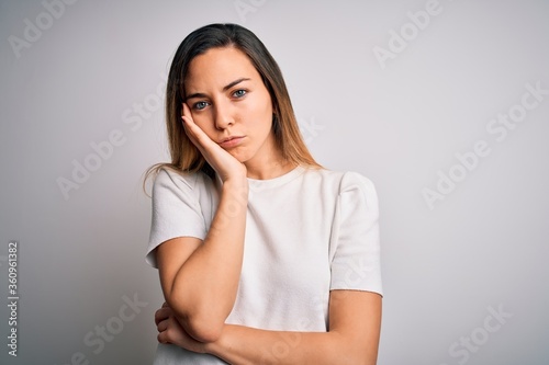 Young beautiful blonde woman with blue eyes wearing casual t-shirt over white background thinking looking tired and bored with depression problems with crossed arms.