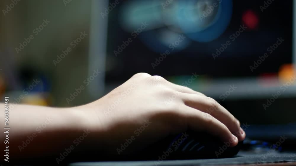 Teenager boy child controls the computer PC mouse with his hand Teenager boy child controls the computer PC mouse with his hand