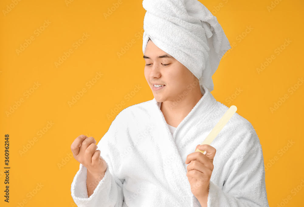 Funny Asian man doing manicure on color background Funny Asian man doing manicure on color background