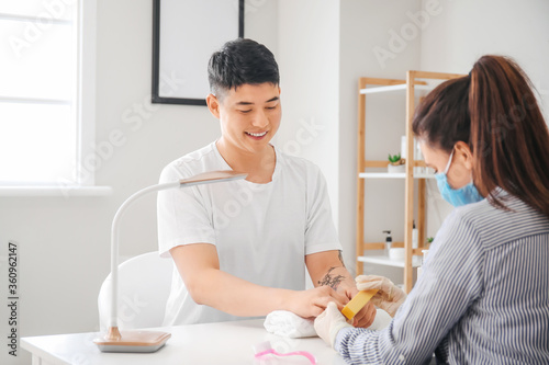 Manicure master working with male client in beauty salon