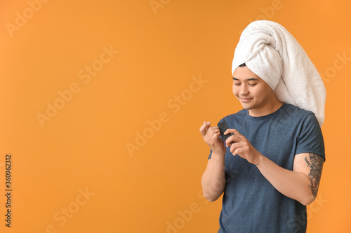 Funny Asian man doing manicure on color background photo